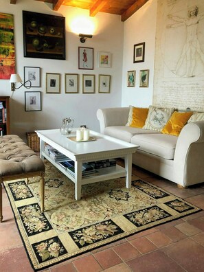 Ein Wohnzimmer mit einem weißen Sofa, einem Couchtisch, einem gemusterten Teppich und gerahmten Bildern an der Wand.