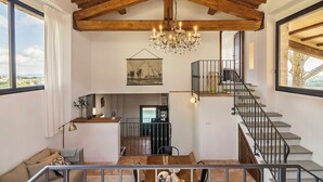 Ein großzügiger Innenraum mit hoher Decke, einer Kristallleuchtre, einer Treppe und Blick durch große Fenster.