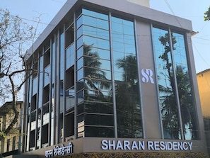 A modern building with the sign 'SHARAN RESIDENCY' and a logo with 'SR' on it. - Sharan Residency (Navi Mumbai)