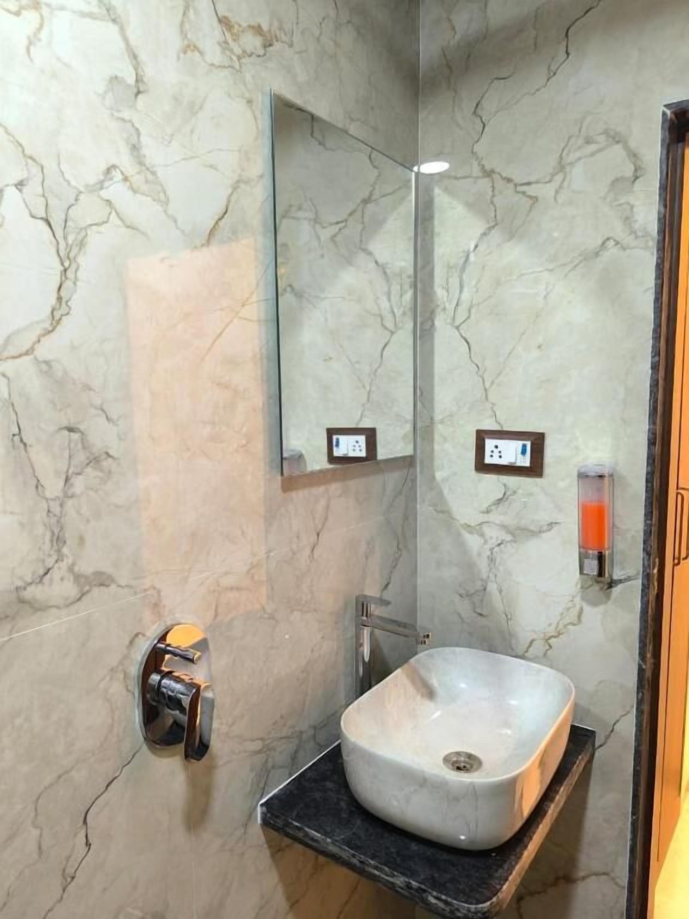 Une salle de bain avec un mur en marbre, un lavabo, un miroir et une douche.