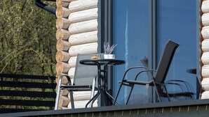 A log cabin with a glass door, a small table with chairs, and a potted plant. - A Charming House with a Garden | Mountain View (Mutne)