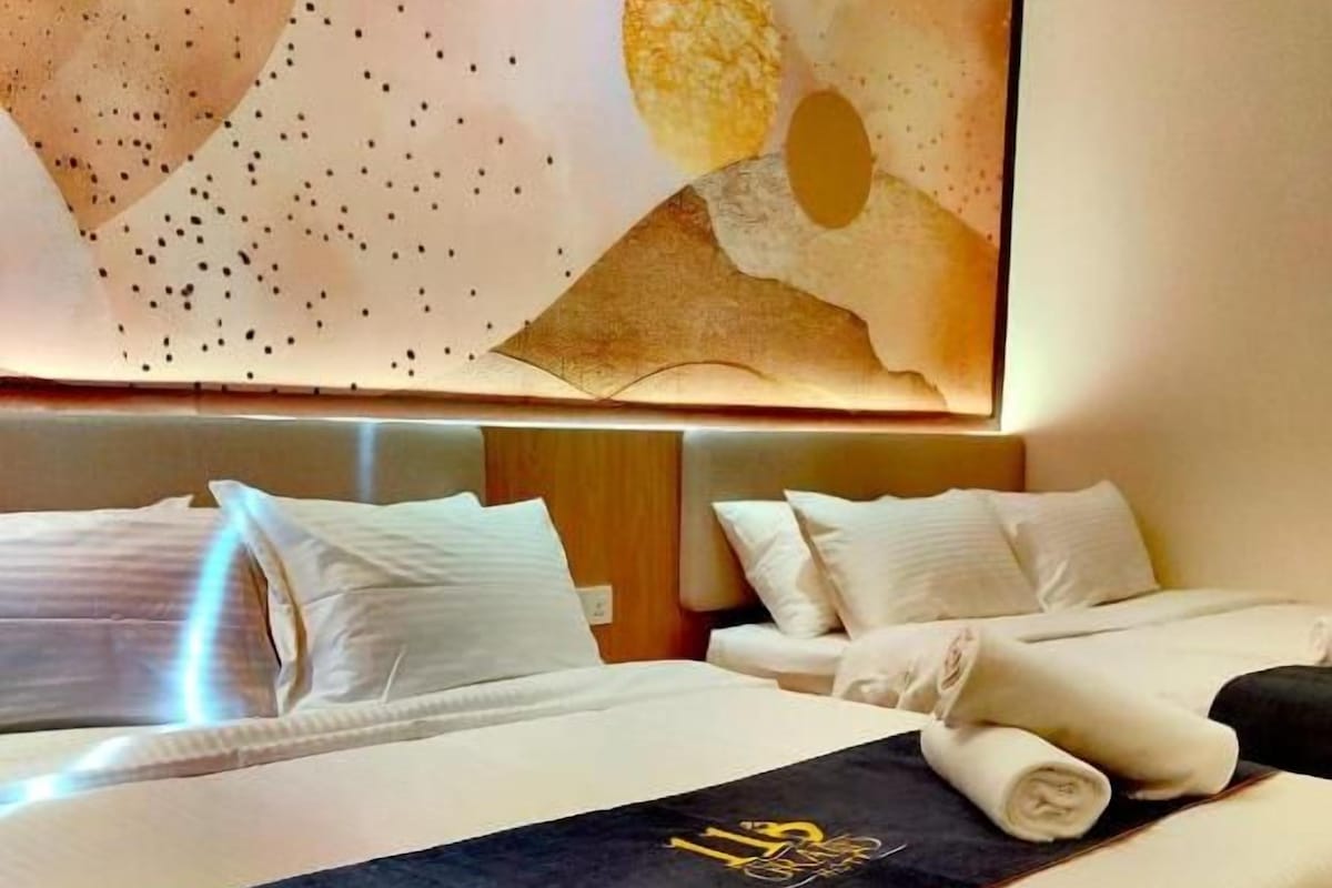 A hotel room with a large bed, a headboard, and a wall with abstract art.