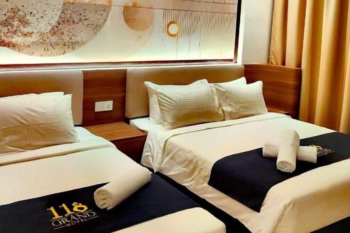 A hotel room with two beds, a large abstract painting on the wall, and a view of the city.