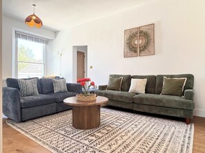Ein Wohnzimmer mit zwei Sofas, einem Couchtisch, einem Teppich mit Muster und einer Wanddekoration.