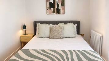 A neatly made bed with a striped blanket, a bedside lamp, and a nightstand with a drawer.
