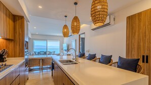 Una cucina moderna con un'isola grande, mobili in legno e sedie in vimini.