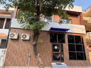 Um edifício com fachada de madeira, janelas amplas e dois aparelhos de ar condicionado fixados na parede.