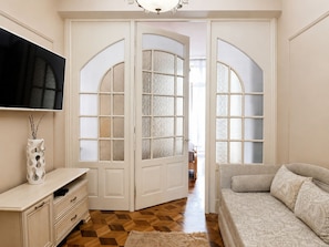 Quarto com televisão, sofá, armário e porta com painéis de vidro.