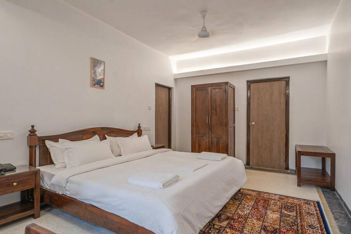 A bedroom with a wooden bed, a nightstand, a bedside table, a wardrobe, and a mirror on the wall.