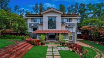 A two-story house with a front entrance, a paved driveway, and a well-maintained garden.