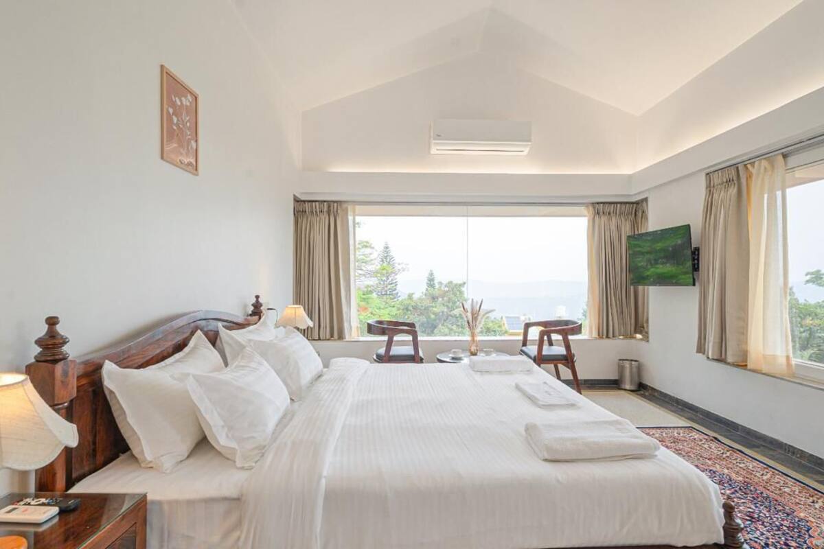 A hotel room with a large bed, a TV, a desk, and a view of the outdoors.