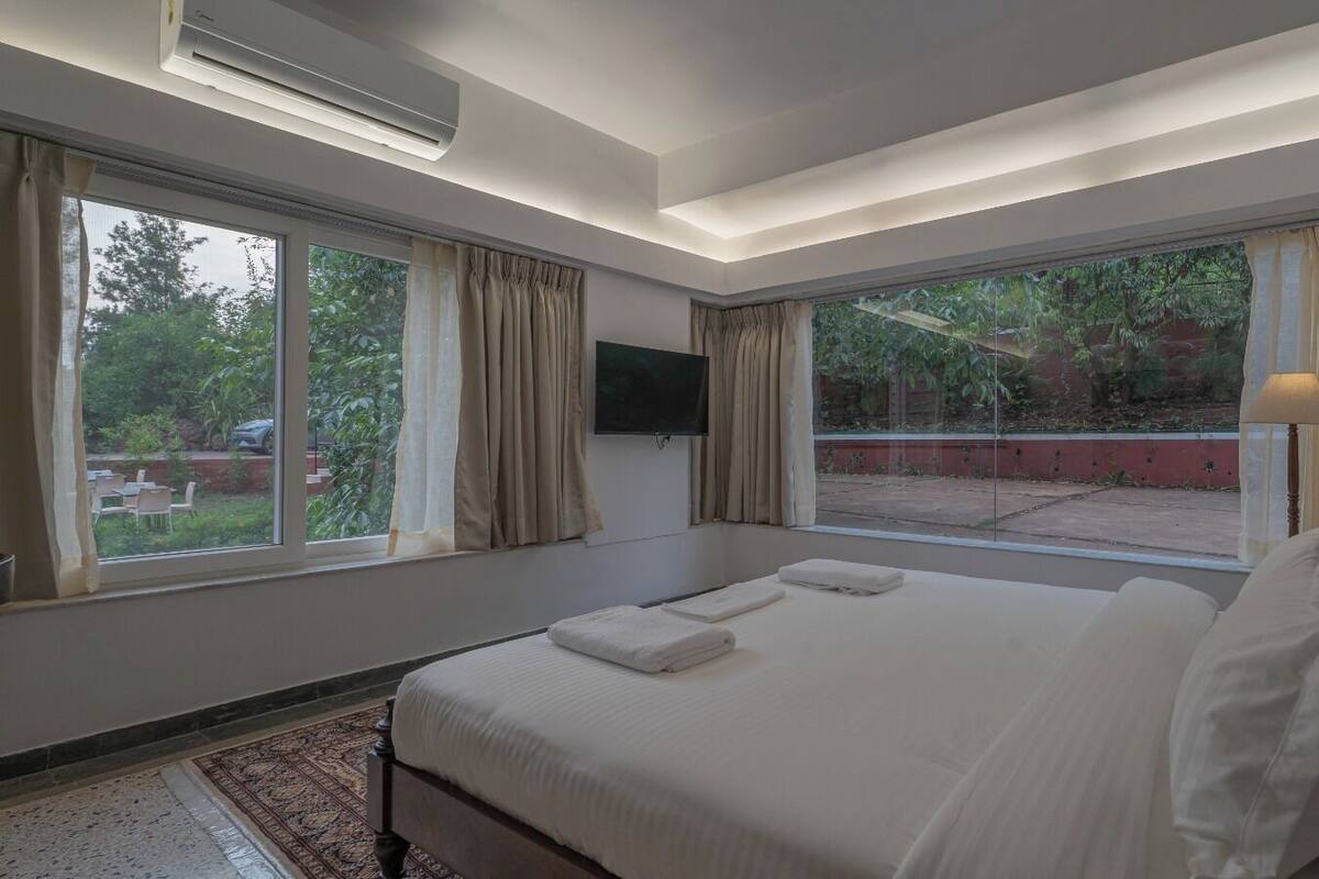 A modern hotel room with a large bed, a flat-screen TV, and a view of the outdoors.