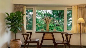 A room with a window, a table, two chairs, a potted plant, and a floor lamp.