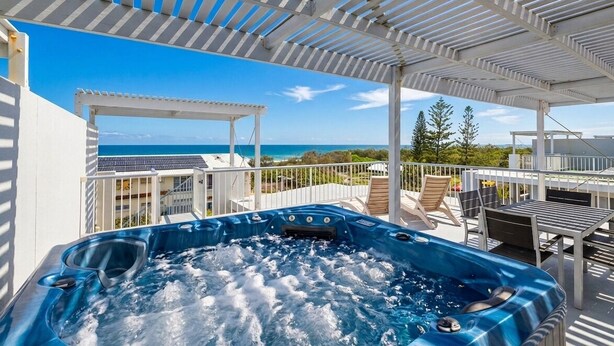 Een bubbelbad op een balkon met uitzicht op de oceaan.