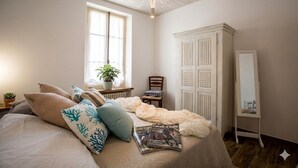 A bedroom with a bed, a window, a potted plant, a chair, a wardrobe, and a mirror. - Casa Sud Miranda - rustico di paese (Borghetto d'Arroscia)
