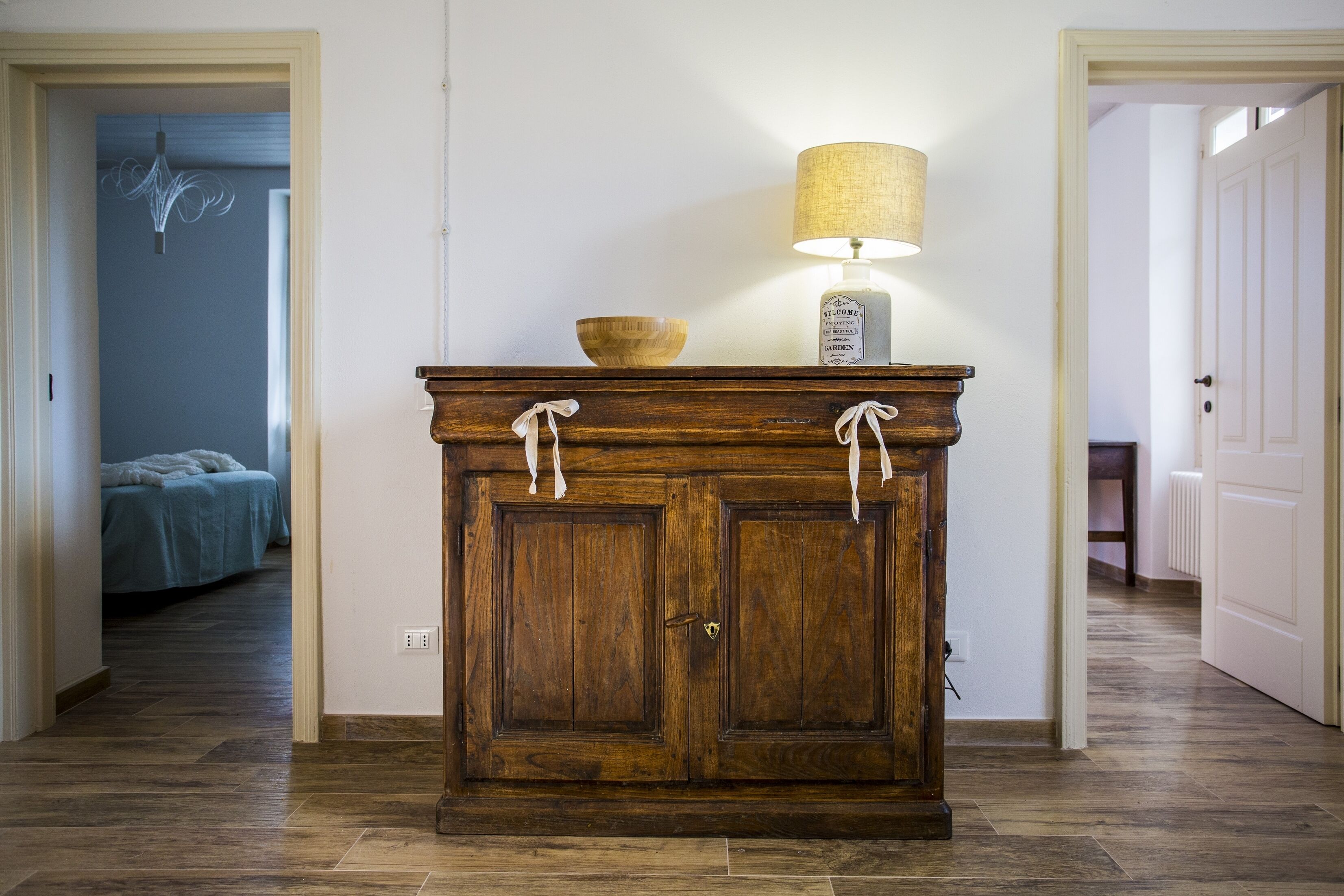 A wooden cabinet with a lamp, a bowl, and a key on top.