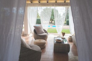 Ein Zimmer mit Korbsessel, Hocker und Glastisch mit Schale und herzförmiger Dekoration.