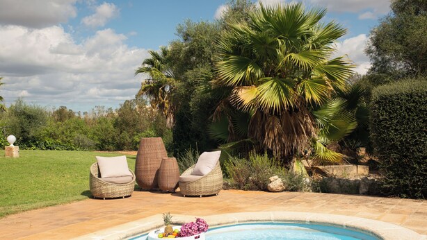 Una piscina con sillas de mimbre y un frutero.
