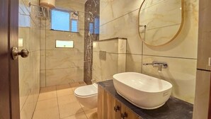 A bathroom with a marble floor, a white sink, a round mirror, and a toilet. - KING PALACE BY VOYE HOMES (Ooty)
