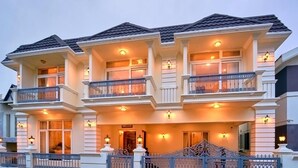A multi-story building with balconies, a gated entrance, and illuminated exterior lighting. - KING PALACE BY VOYE HOMES (Ooty)