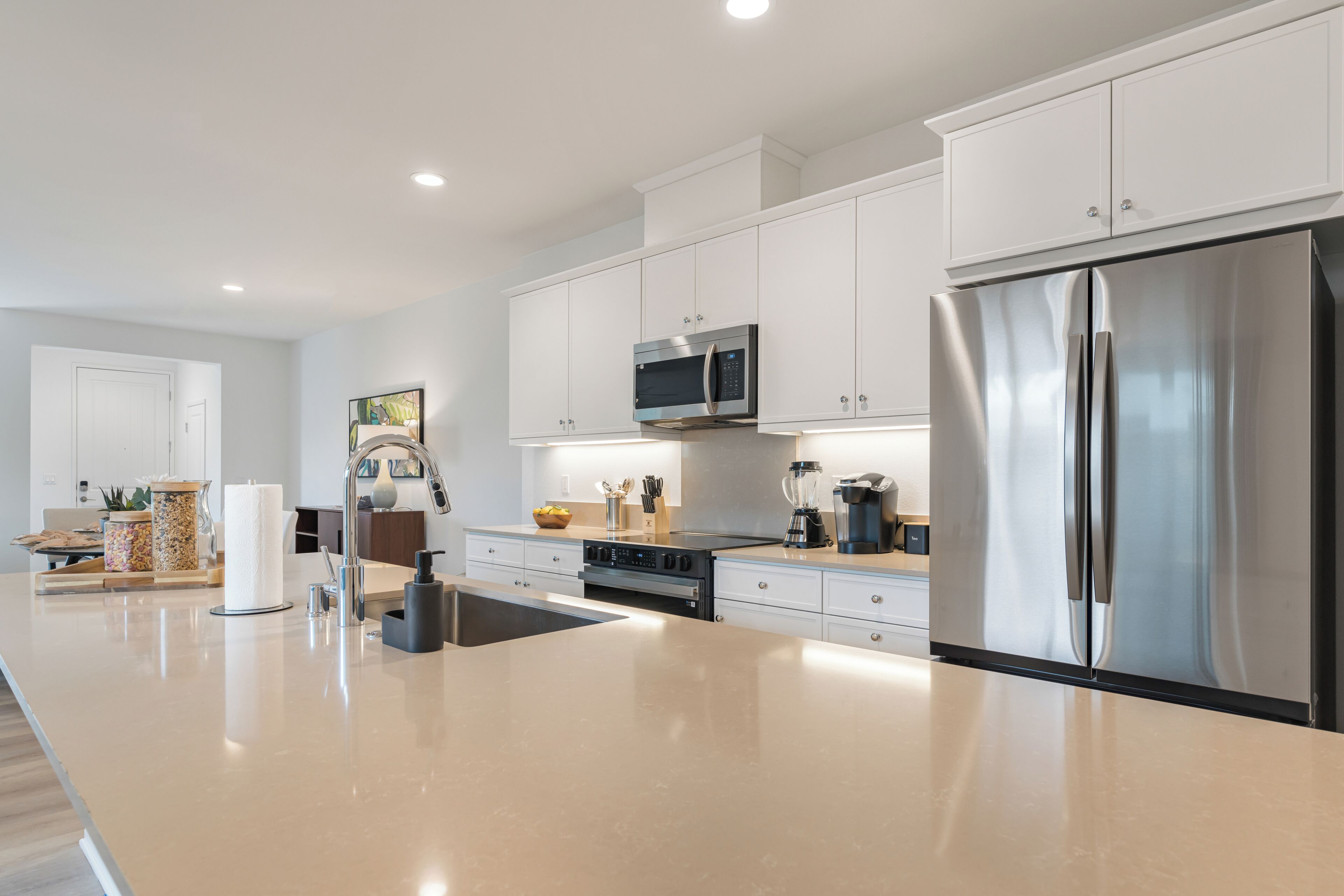 A modern kitchen with white cabinets, stainless steel appliances, and a large island.