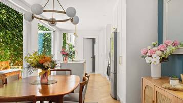 A modern kitchen with a dining area, a chandelier, and a view of greenery outside.