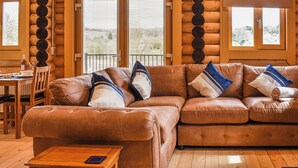 Ein Blockhaushaus-Interieur mit einem braunen Ledersofa, einem Holzesstisch und einer kleinen Holzbank.
