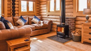 Ein Holzblockhaus-Interieur mit einer Couch, einem Tisch, einem Kamin und einer Lampe.