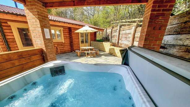 Ein Whirlpool mit einer Holzterrasse und einer Terrasse mit Tisch und Stühlen.