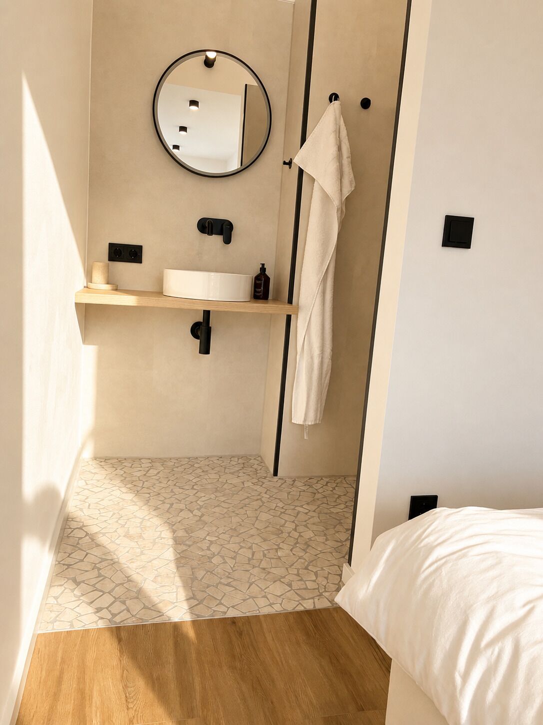 A modern bathroom with a round mirror, a sink, a towel rack, and a shower curtain.