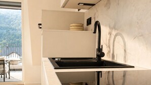 Une cuisine moderne avec un évier noir, des meubles blancs et un pare-feu en marbre.
