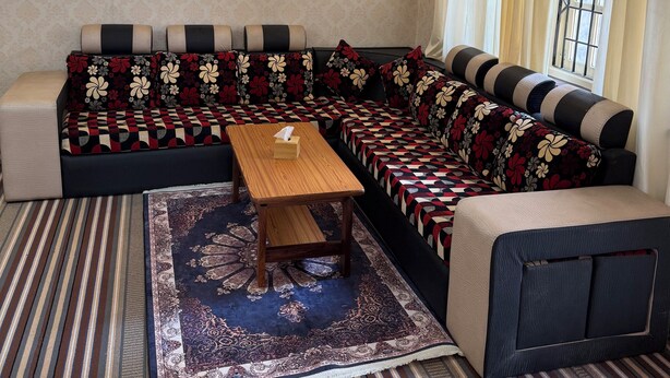 A modern living room with a sectional sofa, a wooden coffee table, and a patterned rug. - Paru home 2bhk Apartment Everest (Kathmandu)