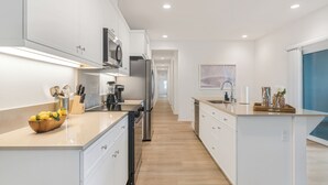 A modern kitchen with white cabinetry, stainless steel appliances, and a wooden countertop. - Entire Building | One 4BR + Two 2BRs | 22 Guests | Resort Pool | Summerwell (La Quinta)