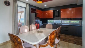 Una cocina moderna con armarios oscuros, una mesa de comedor con sillas y un ventanal amplio.