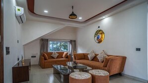 Una sala de estar moderna con un sofá, una mesa de centro, otomanas y un elemento decorativo en la pared.