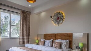Un dormitorio moderno con una cama grande, un cabecero con luz decorativa, una mesita de noche con lámpara y una ventana con cortinas.