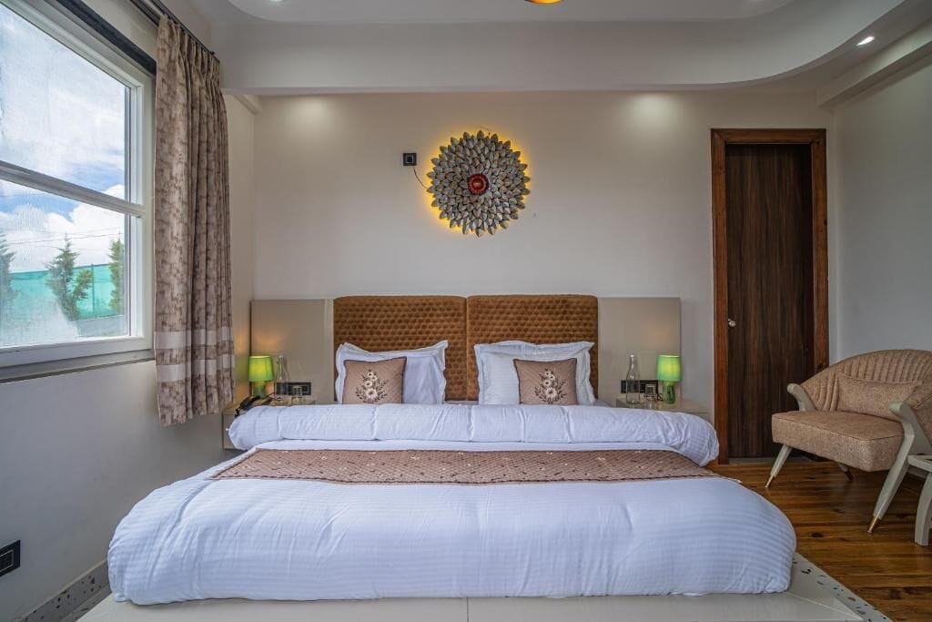 Una camera da letto con un letto grande, due comodini, un elemento decorativo a parete, una finestra con tende e una porta in legno.