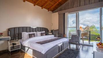 A bedroom with a large bed, a nightstand, a chair, and a view of the outdoors.