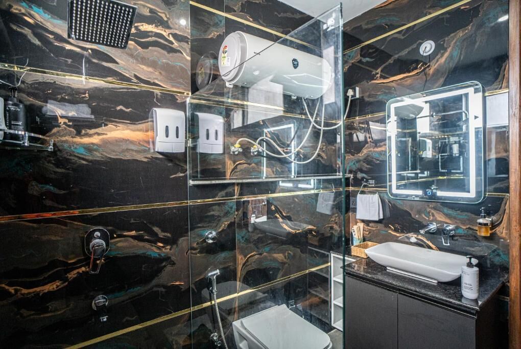 A modern bathroom with a glass enclosure, a white sink, a mirror, and a showerhead.