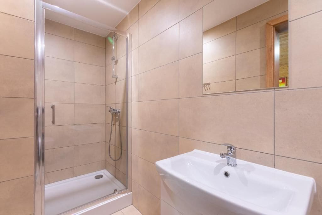 Ein Badezimmer mit Duschkabine, Waschbecken und Spiegel.