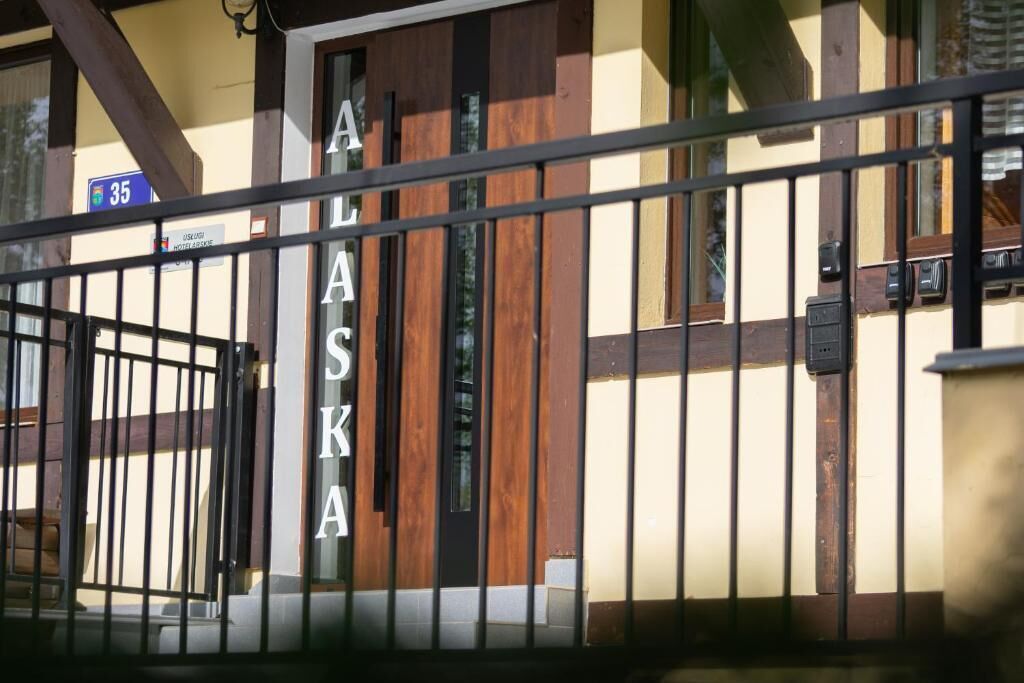 A hotel entrance with a metal gate and a wooden door.