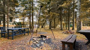 A campsite with picnic tables, a swing set, and a fire pit surrounded by trees. - Willa Alaska (Karpacz)