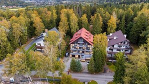 A multi-story building with a red roof, surrounded by dense forest, and a view of a valley in the background. - Willa Alaska (Karpacz)