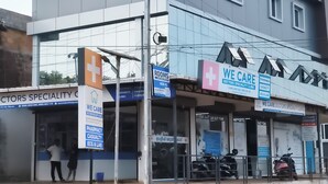 Un edificio con un cartel que indica 'Universal Residency' y 'Clínica Especializada en Medicina We Care', con una farmacia y servicios de emergencia.