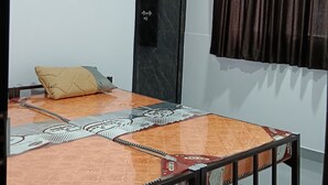 Una habitación con una cama, una puerta y un ventanal con cortinas.