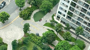 An aerial view of a residential area with a swimming pool, greenery, and a multi-story building.