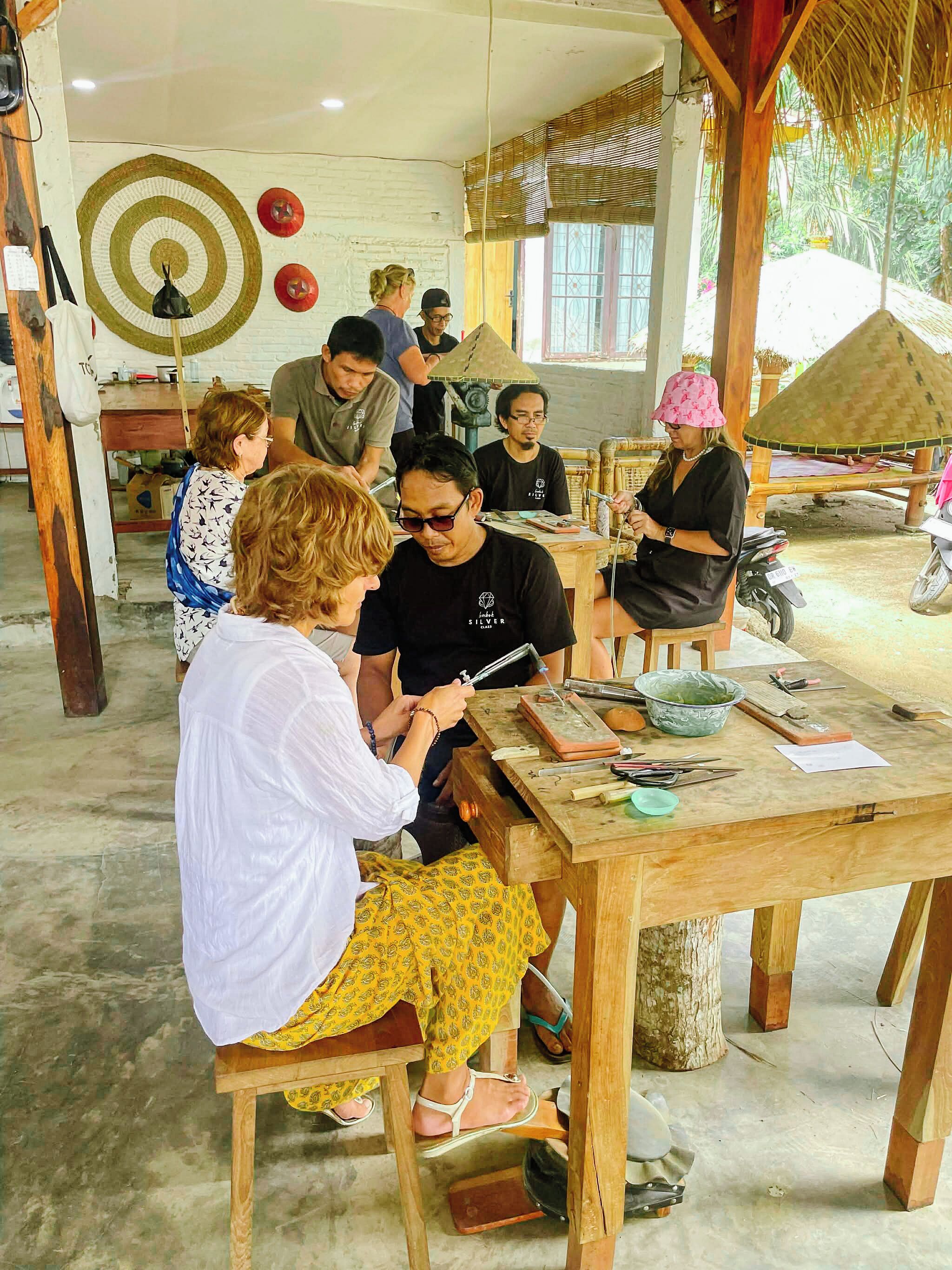 Un atelier où des personnes sont occupées à des activités manuelles, avec des tables en bois et des outils à disposition.