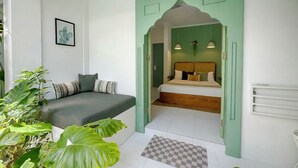 A room with a bed, a green door, a small table, and a plant. - Naia Hotel Kuta Lombok (Kuta)