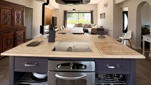 Une cuisine moderne dotée d’un îlot central, d’un four encastré et d’une hotte en acier inoxydable.
