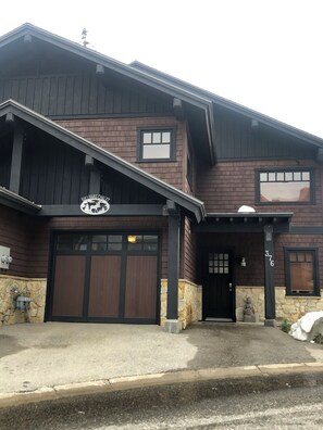 A two-story building with a dark brown facade, a garage, and a stone foundation.